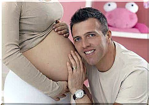 A father with his ear to the belly of his pregnant partner.